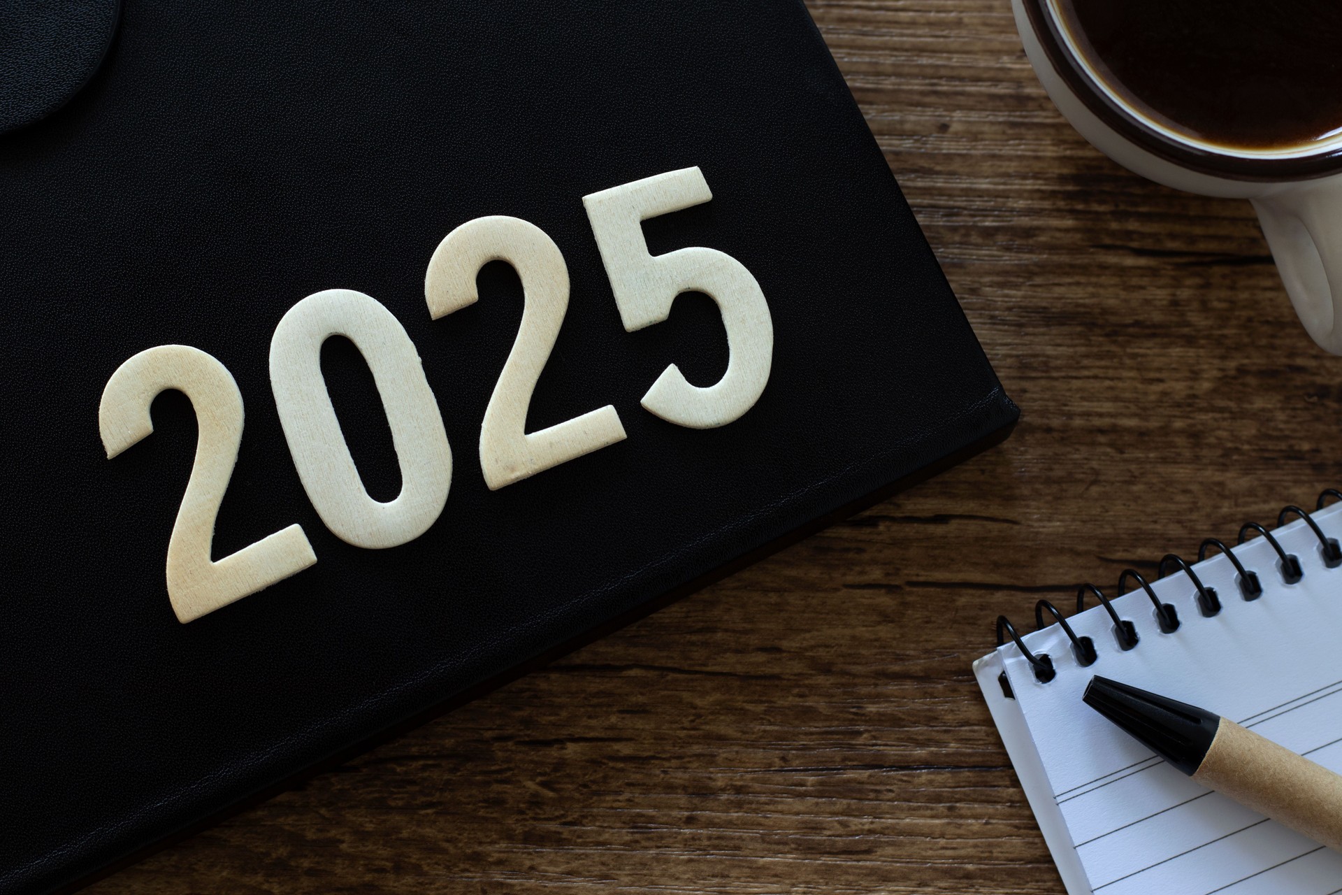 2025 new year wooden number on notebook and coffee cup, top view